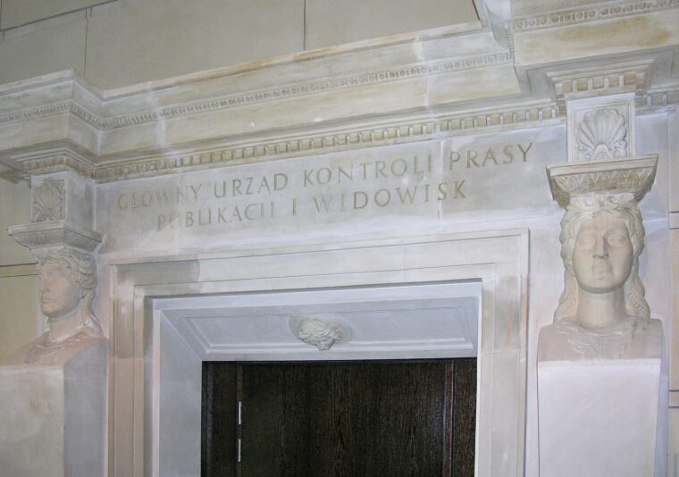 Adrian Grycuk, Zachowany portal ze zburzonego gmachu Głównego Urzędu Prasy, Publikacji i Widowisk w holu biurowca Liberty Corner w Warszawie, Wikimedia Commons, [link do pliku](https://commons.wikimedia.org/wiki/File:Zachowany_portal_G%C5%82%C3%B3wny_Urz%C4%85d_Kontroli_Pras y,_Publikacji_i_Widowisk_Liberty_Corner.JPG), licencja CC BY-SA 3.0 PL.